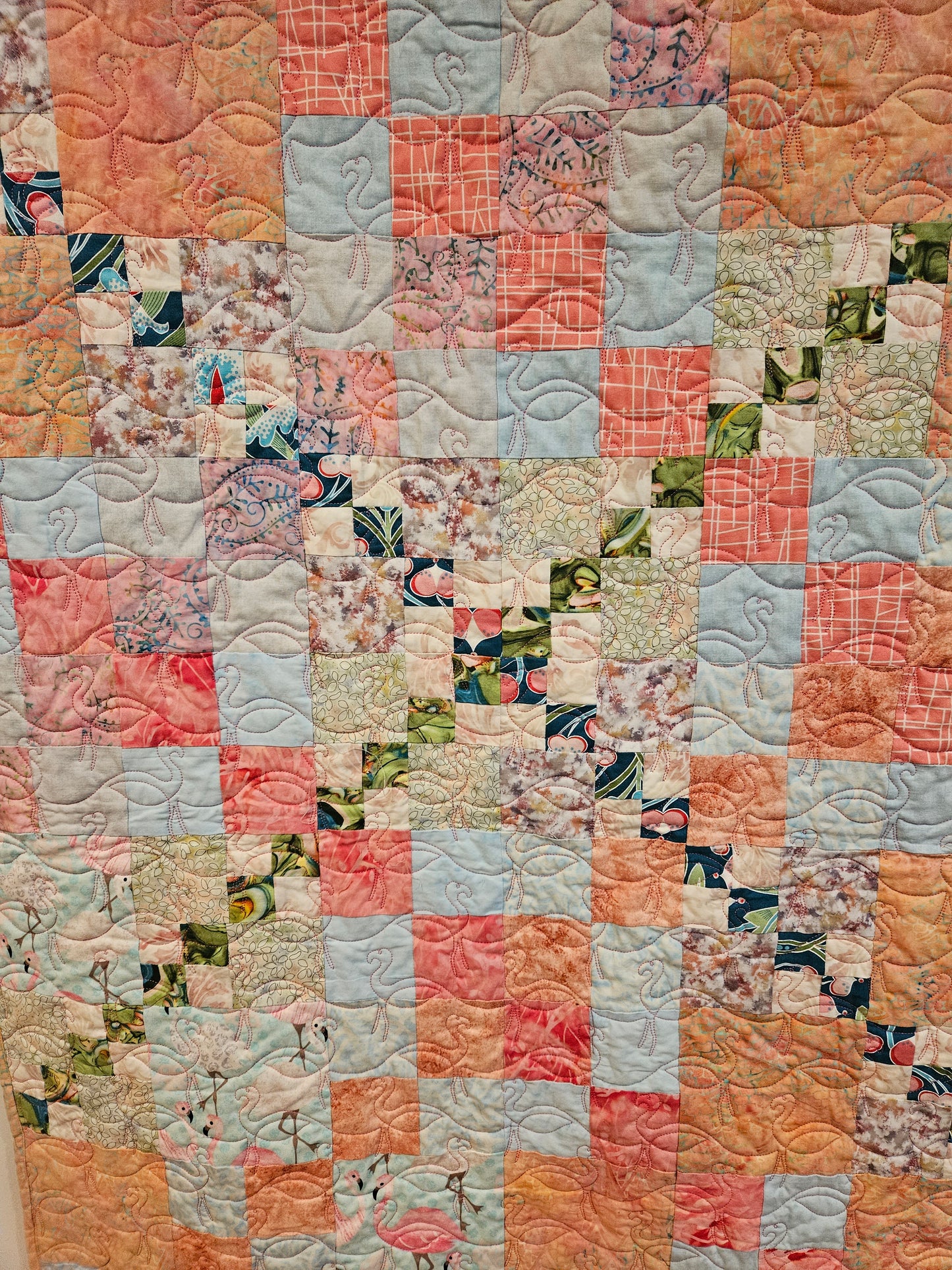 Close up of the crossing of blue and green fabrics in the front of the quilt. You can also see the quilted flamingos.