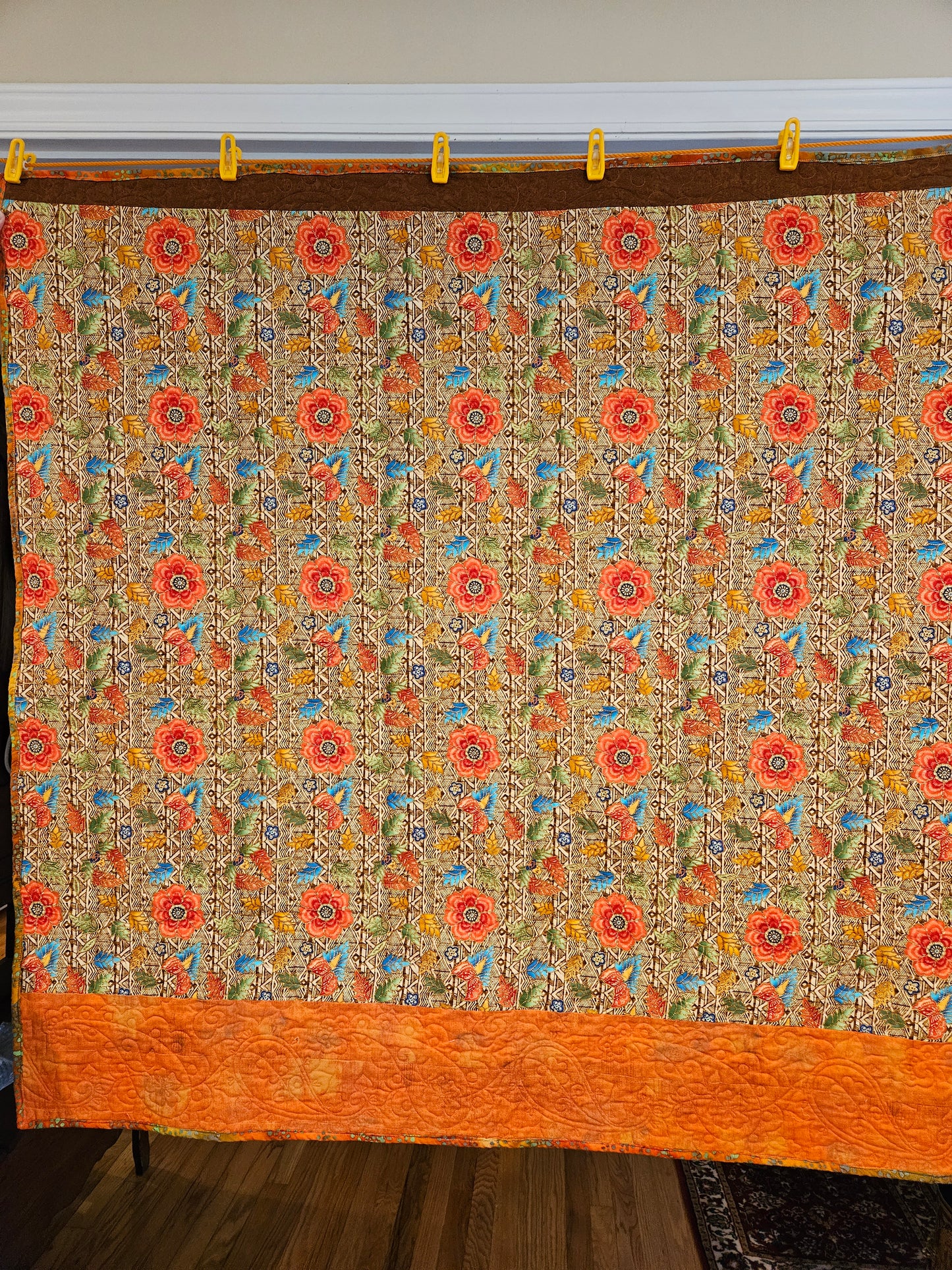 Back of the quilt with the floral fabric and orange trim.