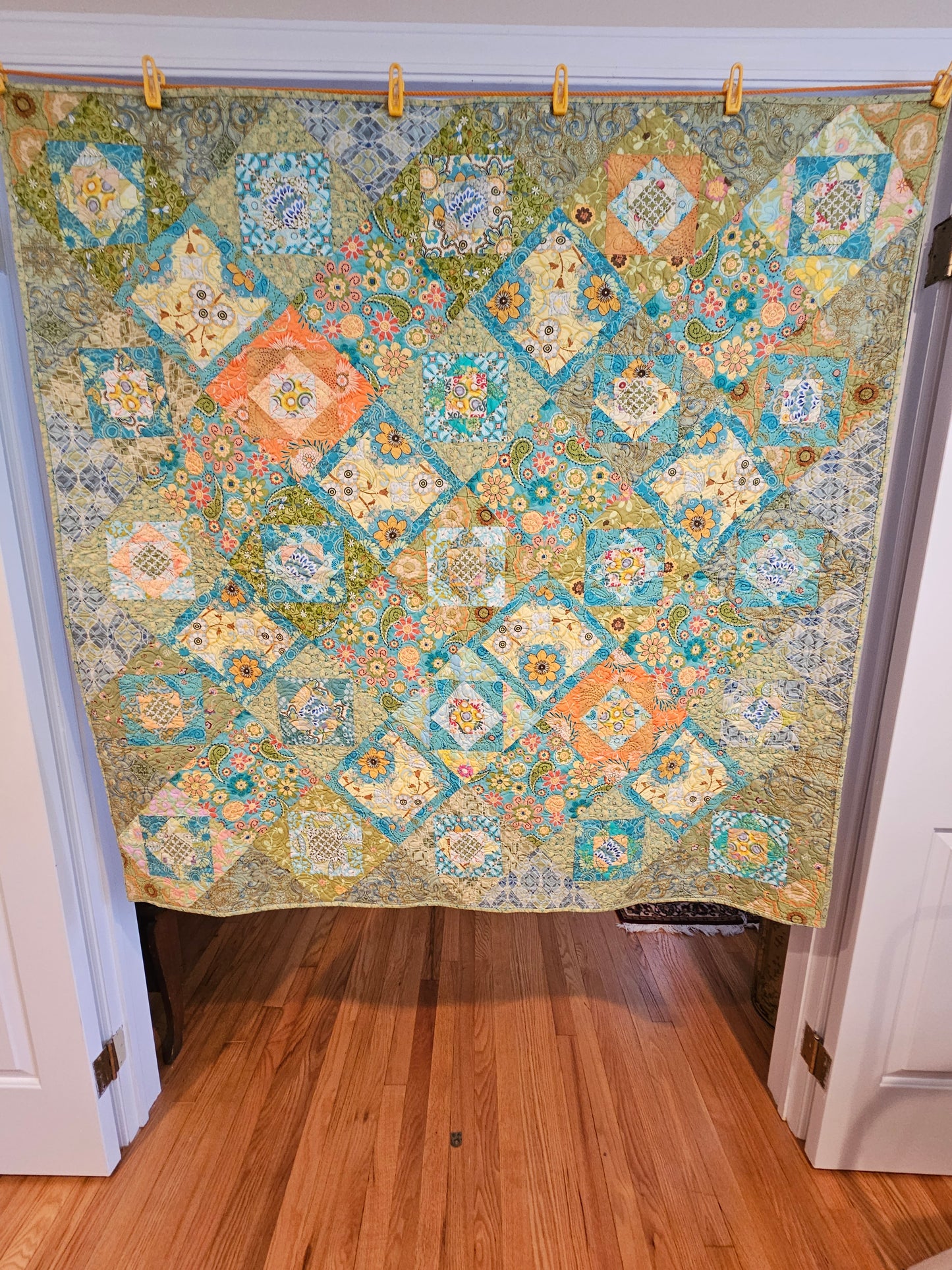 Colorful blue, green, yellow and orange quilt with yellow binding.