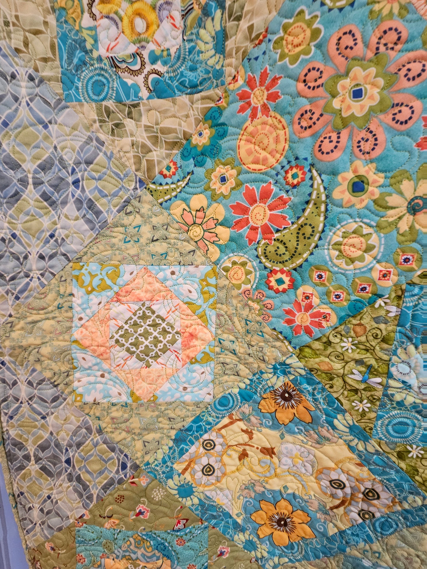 Close-up of a colorful quilt with floral and paisley patterns.