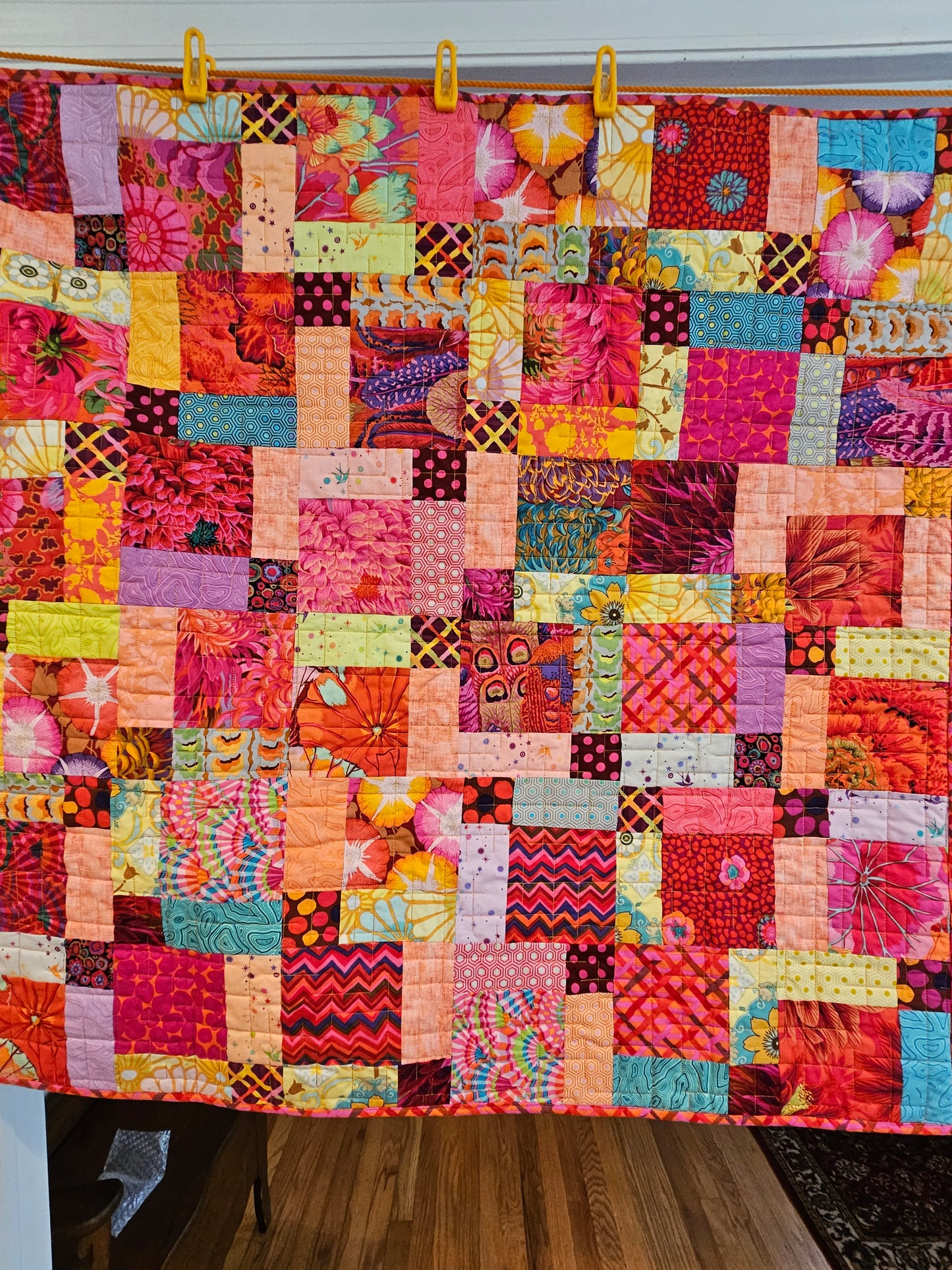 Photo showing the entire Split 9 patch quilt of Kaffe Fassett and Tula Pink fabrics. There are other fabrics in the quilt.