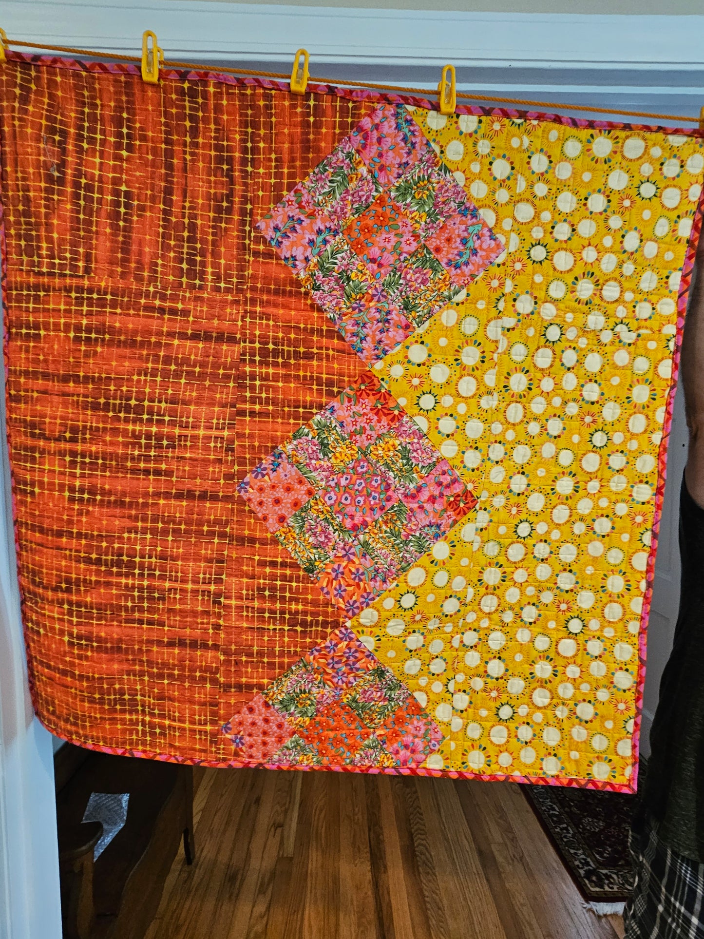 Photo showing the entire back of the quilt. It has red and yellow fabrics divided by Kaffe Fassett nine patches.