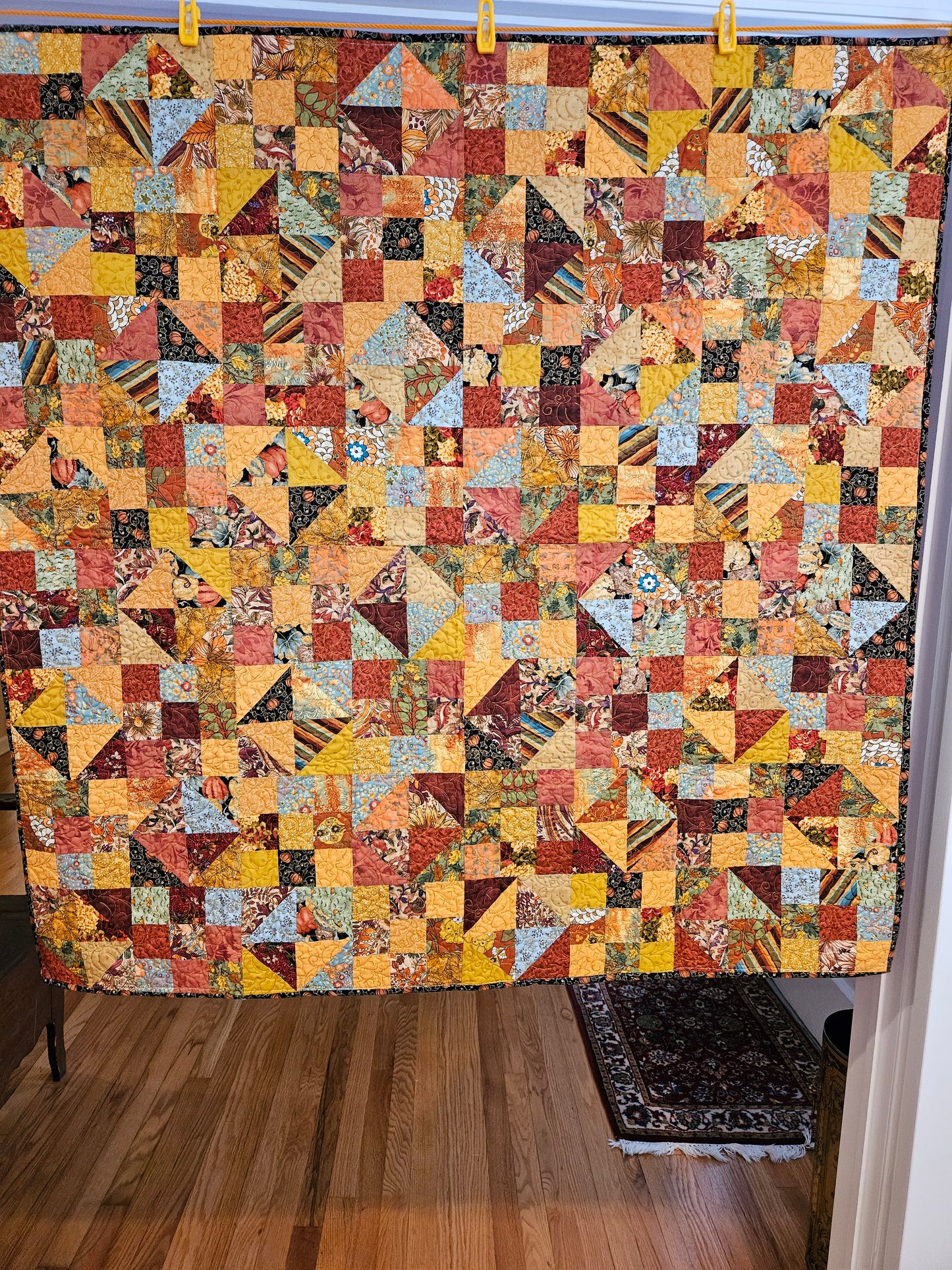 A fall-colored patchwork quilt. A combo of 9 patches and half square triangles.