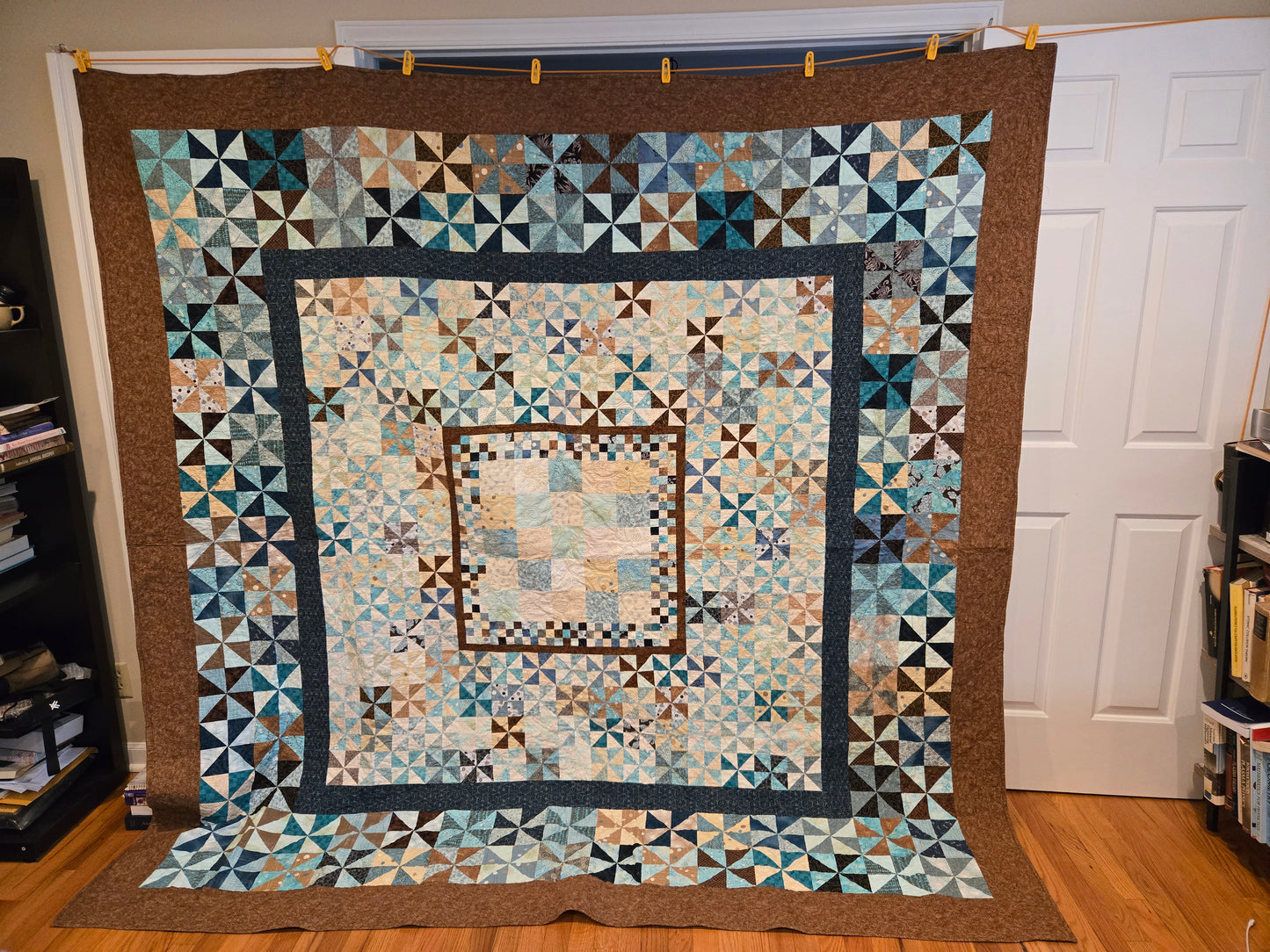 photo of entire quilt. Blue, brown,black and biege. Has a several borders and different scales of blocks.