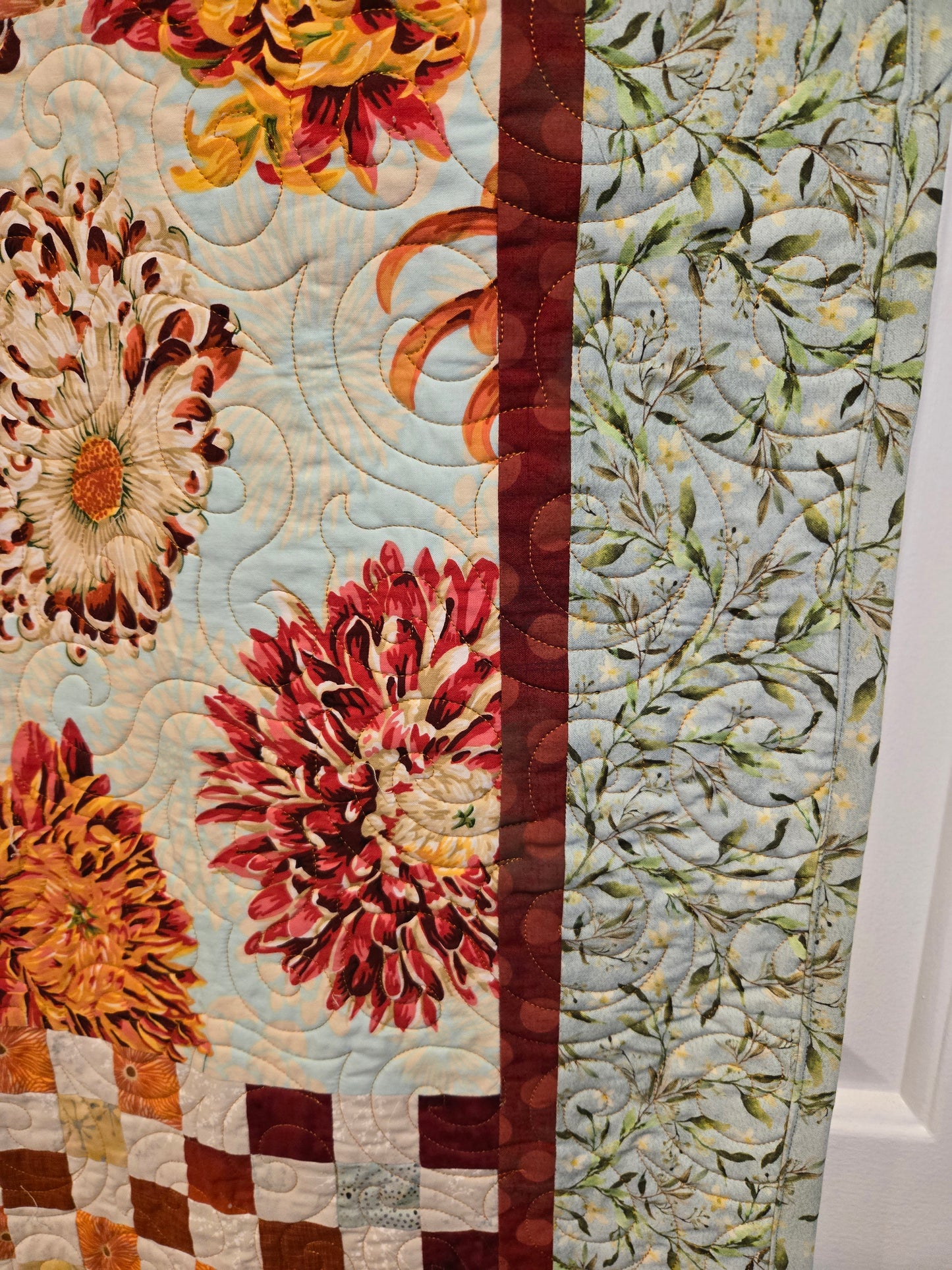 close up of quilt edge. small burgandy border floowed by a blue border with a white/beige flower.