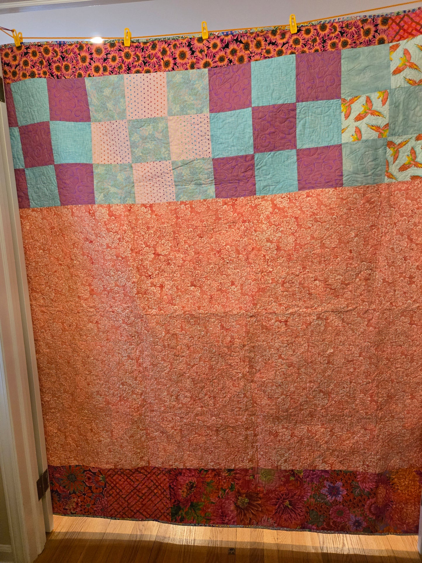 Back of quilt with pink, Kaffe Fassett reds and blue and pink 9 patches.