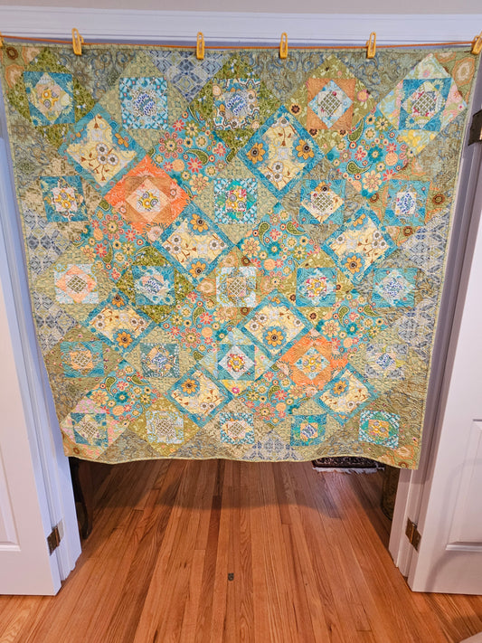 Colorful blue, green, yellow and orange quilt with yellow binding.