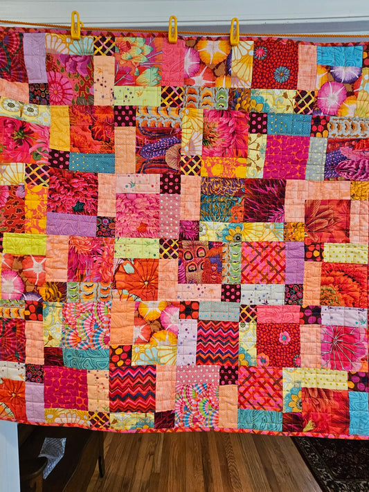 Photo showing the entire Split 9 patch quilt of Kaffe Fassett and Tula Pink fabrics.  There are other fabrics in the quilt.