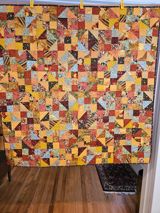 A fall-colored patchwork quilt. A combo of 9 patches and half square triangles.